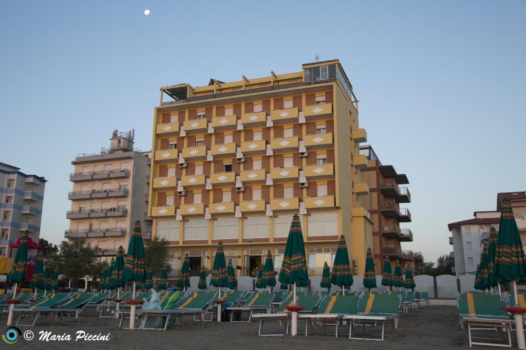 un bâtiment avec des chaises et des parasols en face de celui-ci dans l'établissement Hotel Apollonia, à Lido di Savio