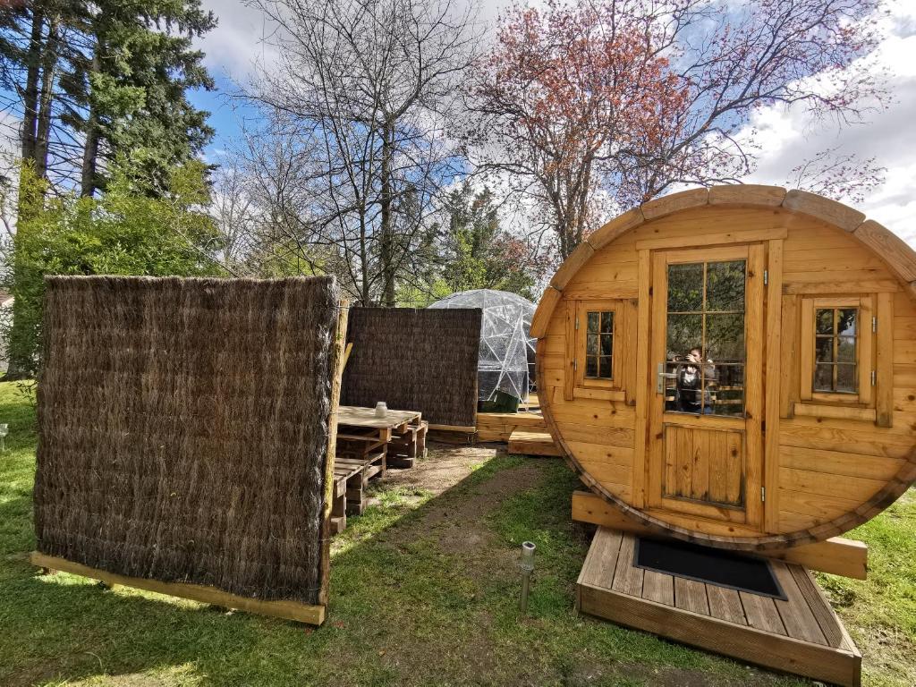 une grande maison en bois dans une cour dans l'établissement sublime tonneau avec spa sous bulle privatif, à Lanthenay