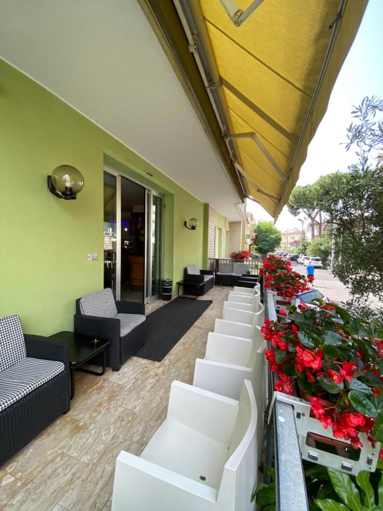 une rangée de chaises blanches et de fleurs sur un bâtiment dans l'établissement Hotel Tre Stelle, à Rimini