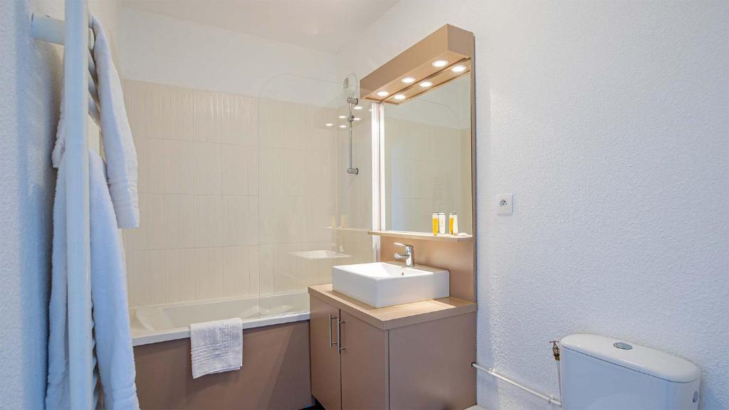 une salle de bain avec un lavabo, des toilettes et un miroir dans l'établissement Madame Vacances Les Terrasses De Véret, à Flaine