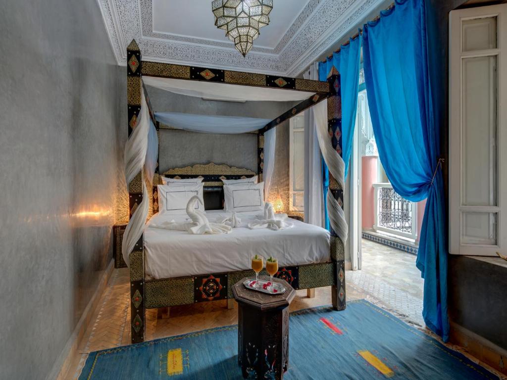 - une chambre avec un lit à baldaquin et des rideaux bleus dans l'établissement Riad Princesse Du Désert & Spa, à Marrakech
