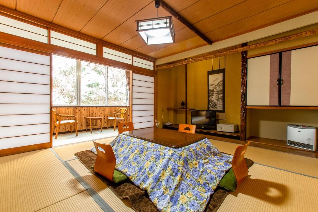 un salon avec une table, des chaises et des fenêtres dans l'établissement Oyado Hisaya, à Kami