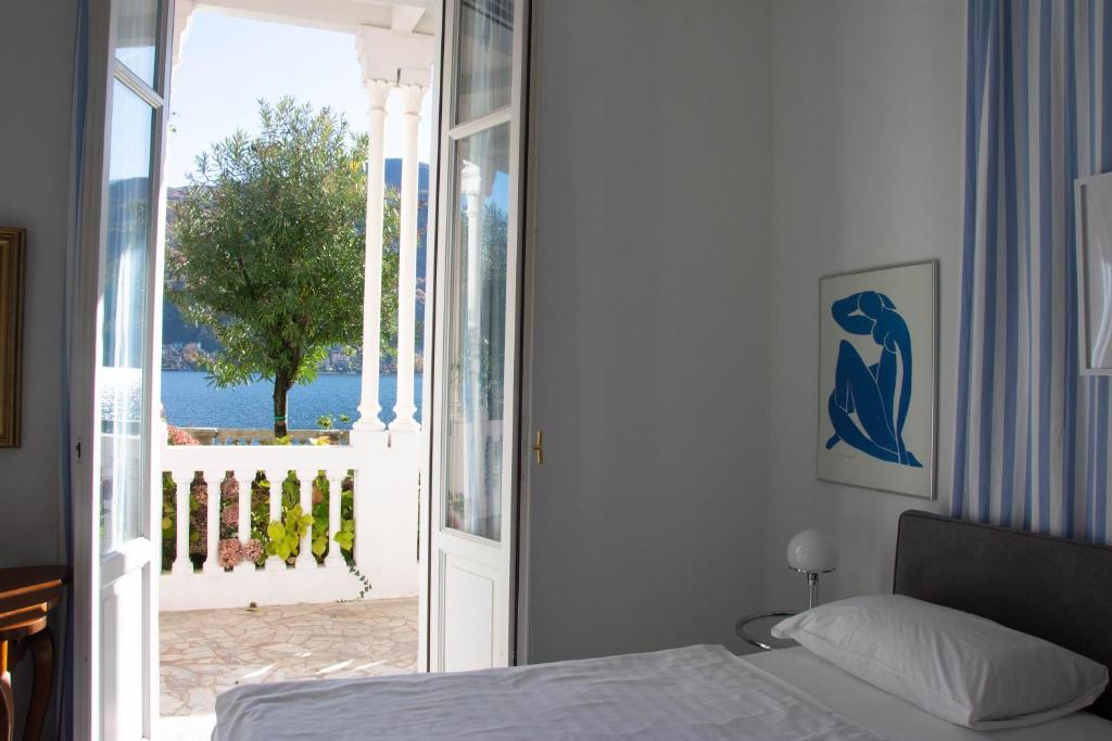 une chambre avec un lit et une porte donnant sur un balcon dans l'établissement Residence Ville Lago Lugano, à Porto Ceresio