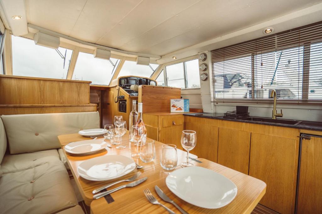 une table en bois avec des assiettes et des verres à vin dessus dans l'établissement NO LIMIT CHARTER bateau avec parking privé proche centre-ville, à Rouen