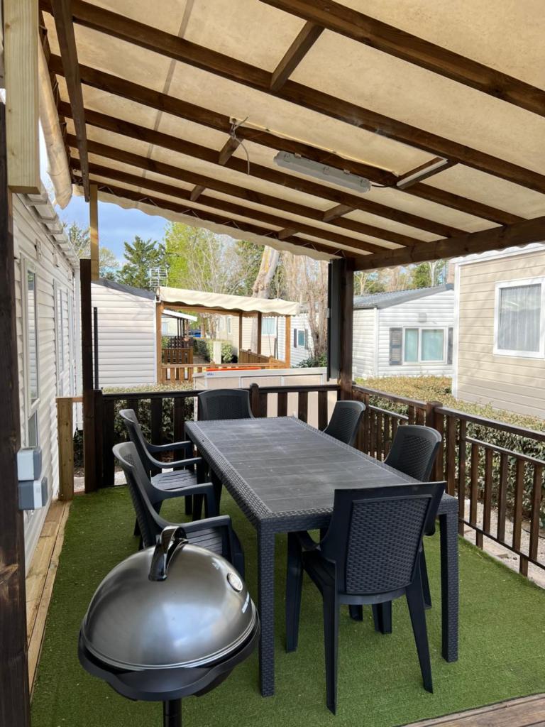 un patio avec une table et des chaises sur une terrasse dans l'établissement Mobilhome Vias Plage la Carabasse, à Vias