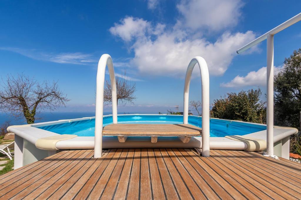une terrasse en bois avec un banc à côté d'une piscine dans l'établissement Villa Novanta, à Massa Lubrense