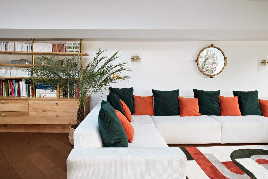 - un salon doté d'un canapé blanc avec des oreillers orange et verts dans l'établissement Escale Sur Seine, à Paris
