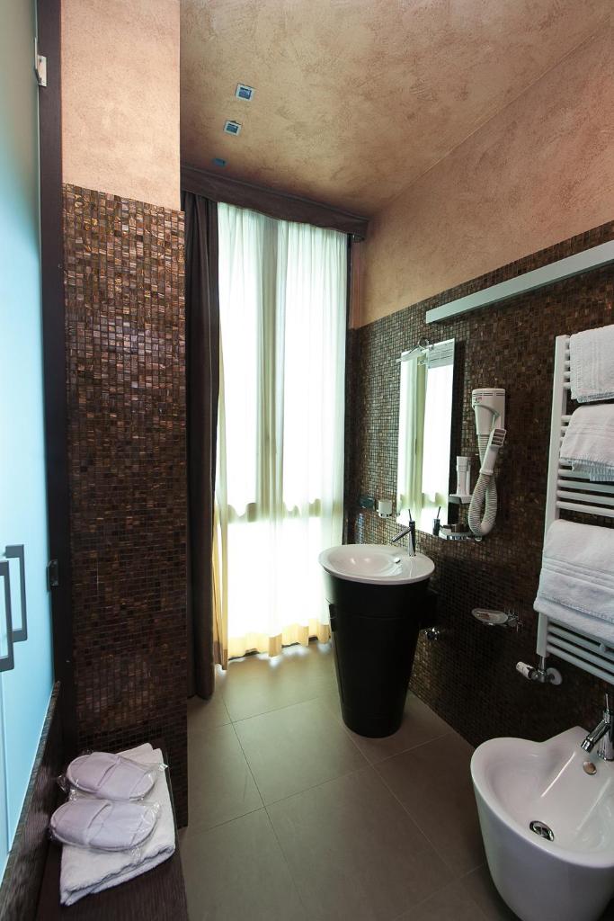 une salle de bain avec un lavabo, une baignoire et un miroir dans l'établissement Hotel Aurora, à Sirmione
