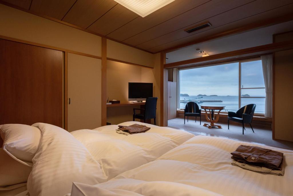 une chambre avec un grand lit blanc avec vue sur l'océan dans l'établissement IKI RETREAT by Onko Chishin, à Iki