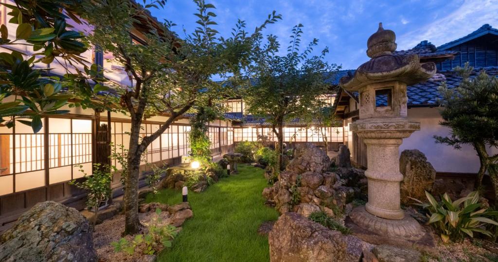 un jardin avec une statue en pierre en face d'un bâtiment dans l'établissement Kakujoro, à Tahara