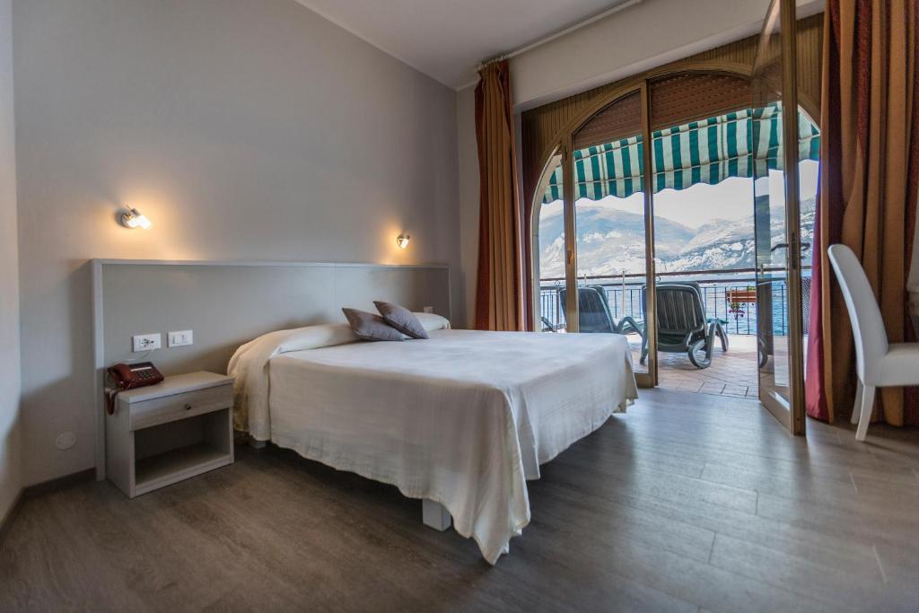 une chambre d'hôtel avec un lit et une grande fenêtre dans l'établissement Hotel Nettuno, à Brenzone