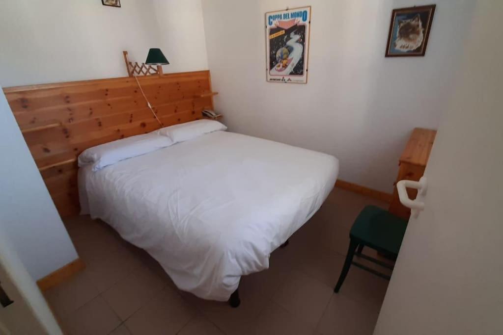 une chambre avec un lit blanc et une chaise verte dans l'établissement Briançon GRANDE TORINO SKYWAY, à Briançon