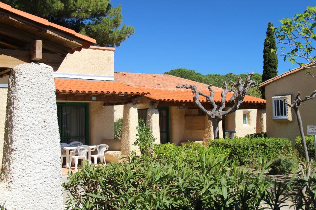 une maison avec une table et des chaises dans une cour dans l'établissement Village vacances & camping de Gruissan, à Gruissan