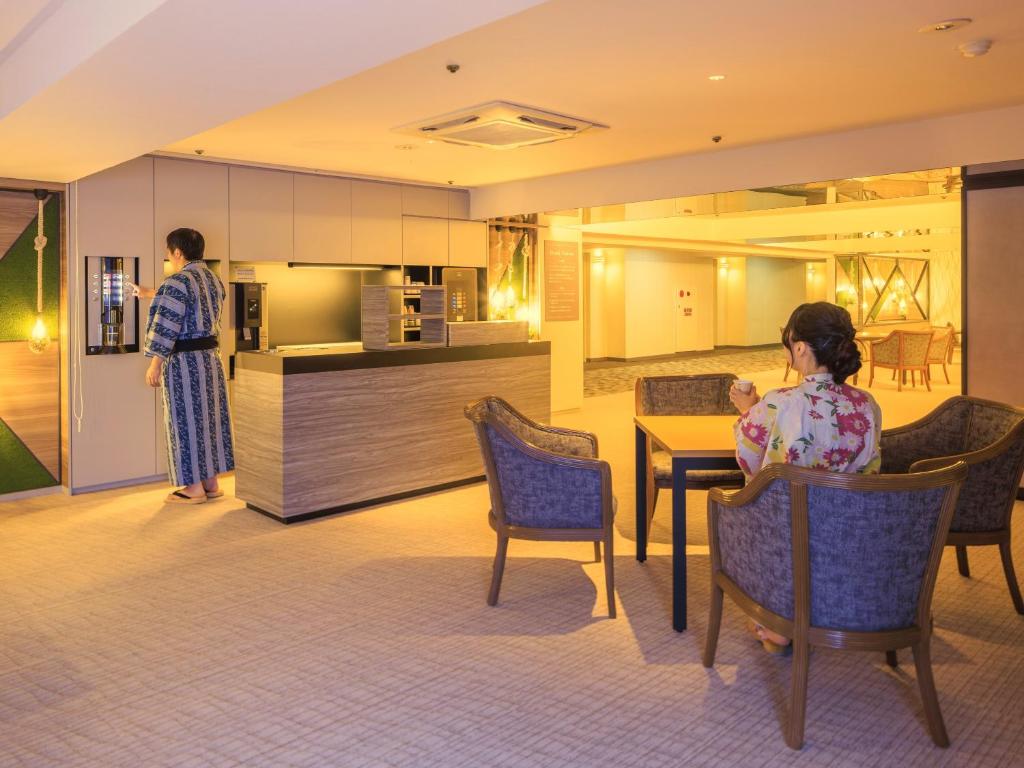 un homme et une femme assis sur des chaises dans une cuisine dans l'établissement Hotel Sanrakuso, à Shirahama