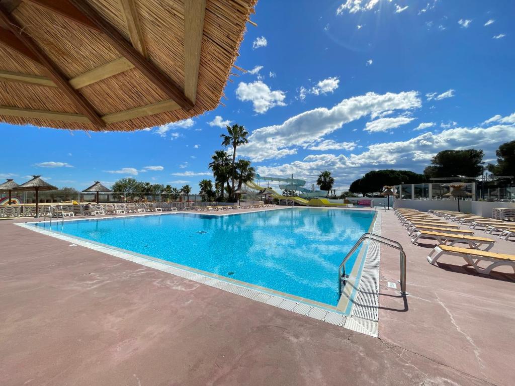 une grande piscine avec des chaises et un ciel bleu dans l'établissement Camping le lac des rêves L'ABRIZEN, à Lattes