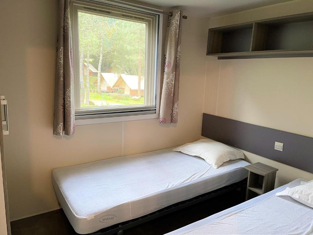 une petite chambre avec deux lits et une fenêtre dans l'établissement Camping Olva ***, à Sartène