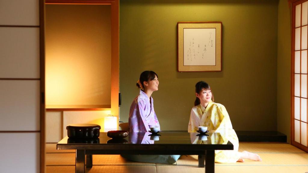 Deux femmes en kimonos debout dans une pièce dans l'établissement Ooedo Onsen Monogatari Higashiyama Grand Hotel, à Aizuwakamatsu