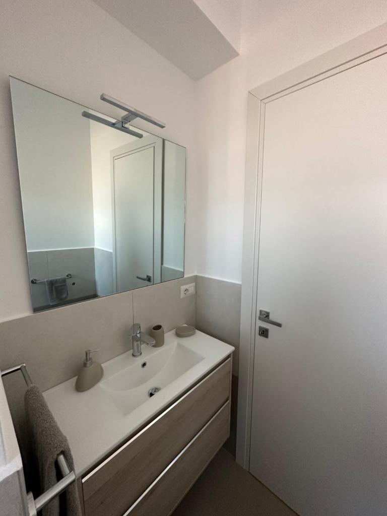 une salle de bain blanche avec un lavabo et un miroir dans l'établissement Rubino apparthotel - Portorosa, à Furnari