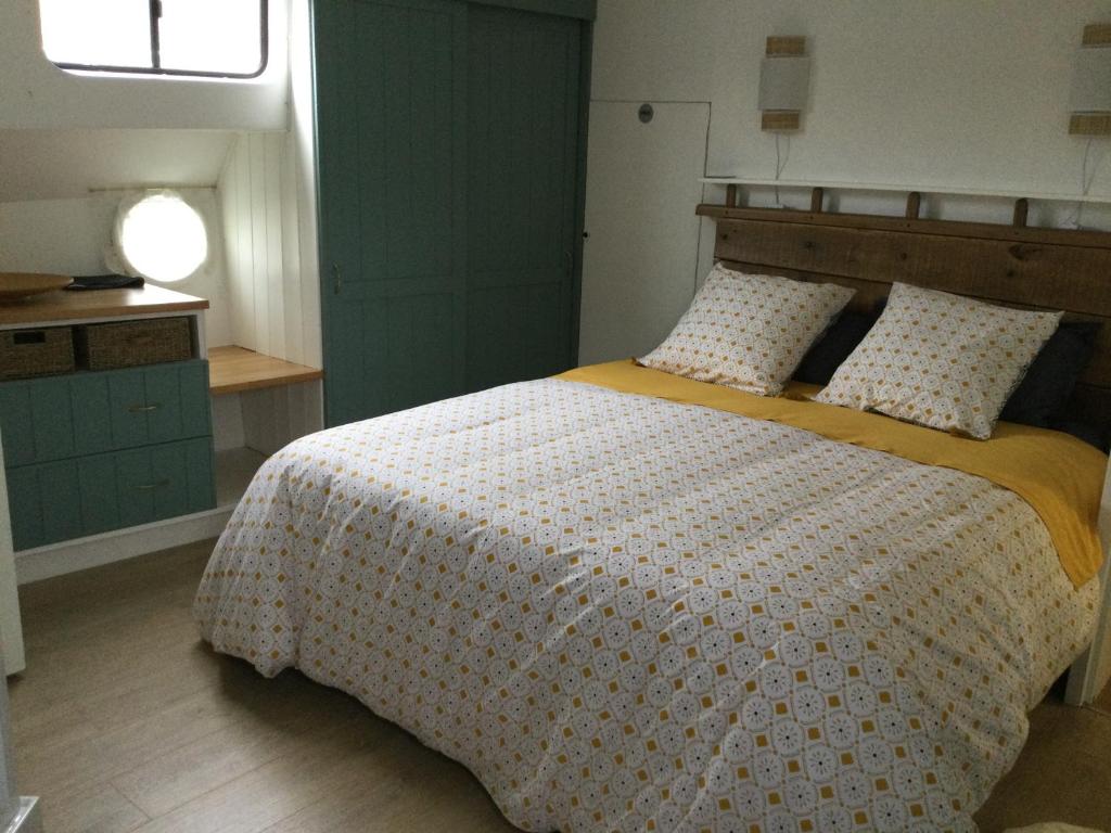 une chambre avec un grand lit avec une couverture jaune dans l'établissement Péniche GEMJO, à Castelsarrasin