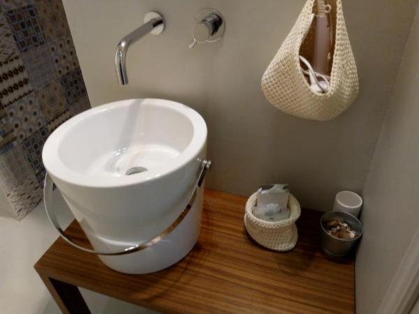 La salle de bains est pourvue d'un lavabo blanc sur une table en bois. dans l'établissement Albergo Aquila, à Rimini