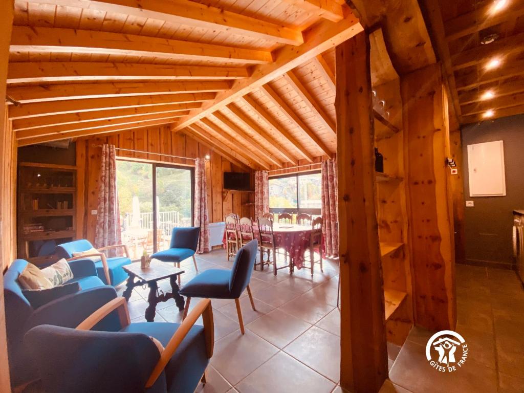 Il comprend un salon doté de plafonds en bois, de chaises bleues et d'une table. dans l'établissement Atalaya - Maître de Cabestany - Gîte avec piscine pour 8 personnes - 3 chambres en suite, à Llo