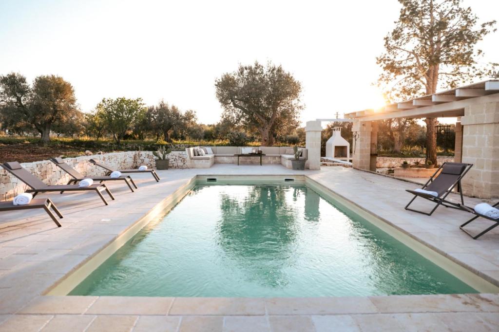 une piscine à débordement avec chaises longues et un patio dans l'établissement Trullo Mamas, à Ostuni