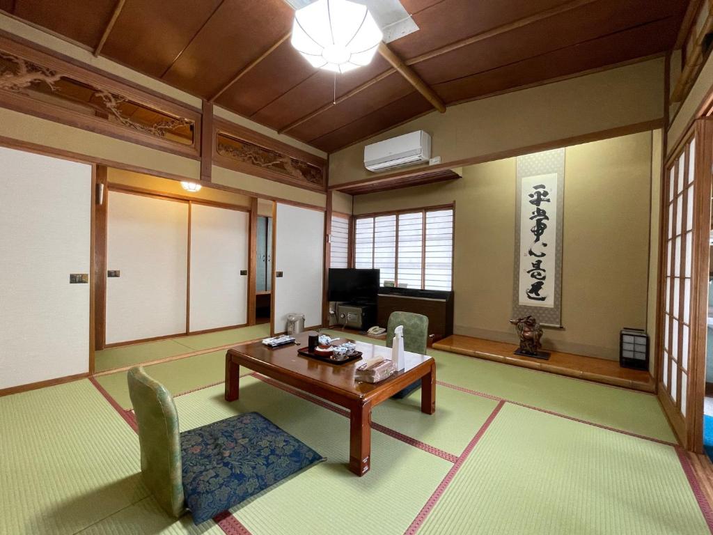 un salon avec une table, des chaises et une télévision dans l'établissement Sakaenoyu Ryokan, à Matsumoto