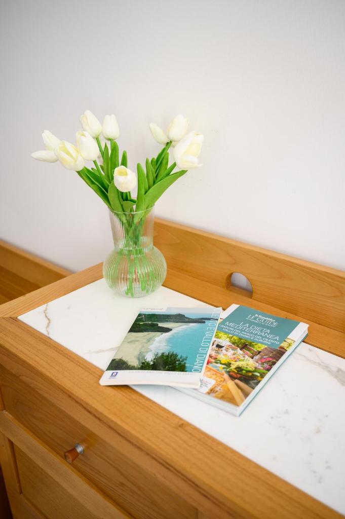 un vase avec des fleurs blanches et un magazine sur une table dans l'établissement Grand Hotel San Pietro, à Palinuro