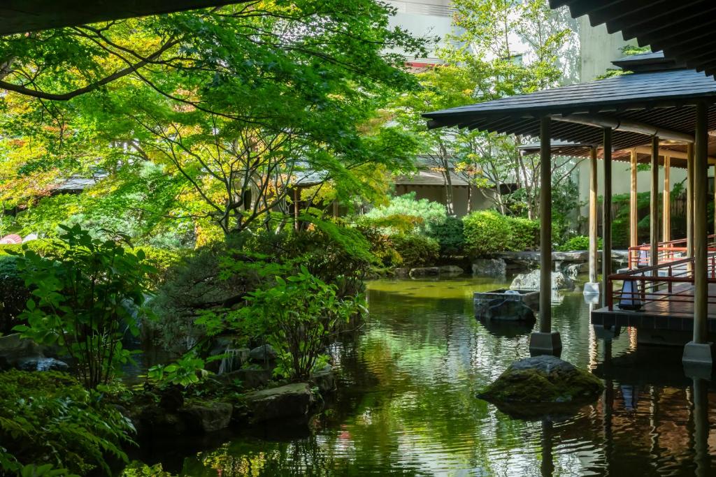 un jardin avec un étang et un bâtiment dans l'établissement Kinugawa Grand Hotel Yumenotoki, à Nikkō