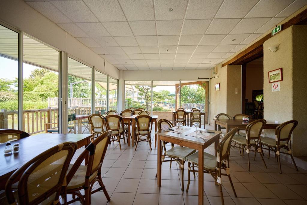 une salle à manger avec tables, chaises et fenêtres dans l'établissement Glamping Gien, à Poilly-lez-Gien