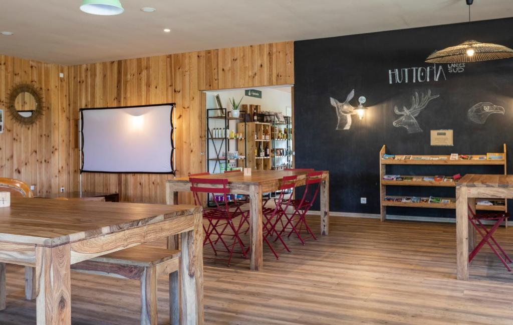 un restaurant avec des murs et des tables en bois et un écran dans l'établissement Huttopia Landes Sud, à Saint-Michel-Escalus