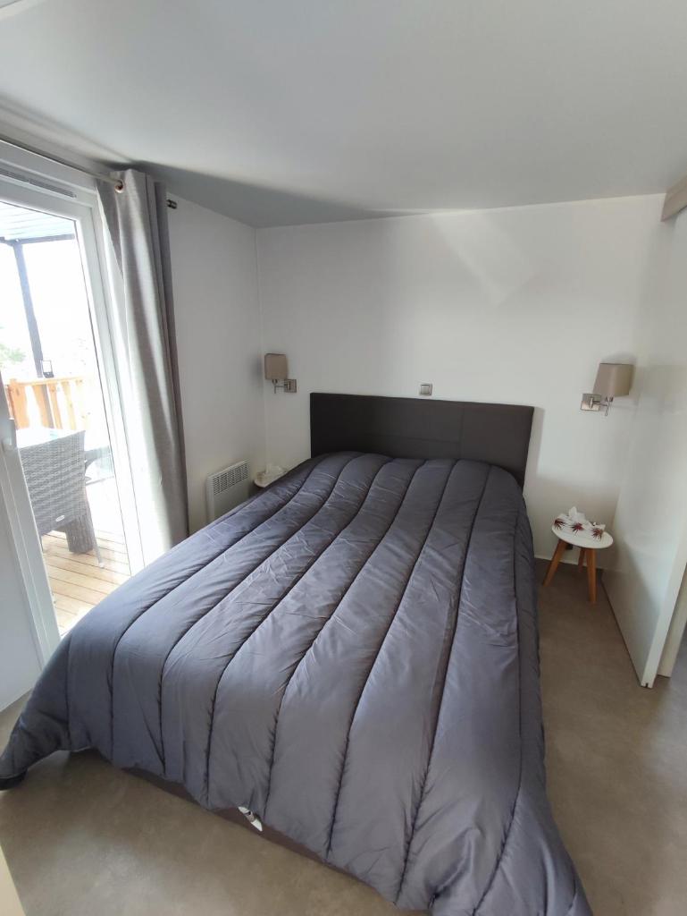un grand lit dans une chambre avec une grande fenêtre dans l'établissement LUXUEUX MOBIL-HOME, à Pierrefeu-du-Var