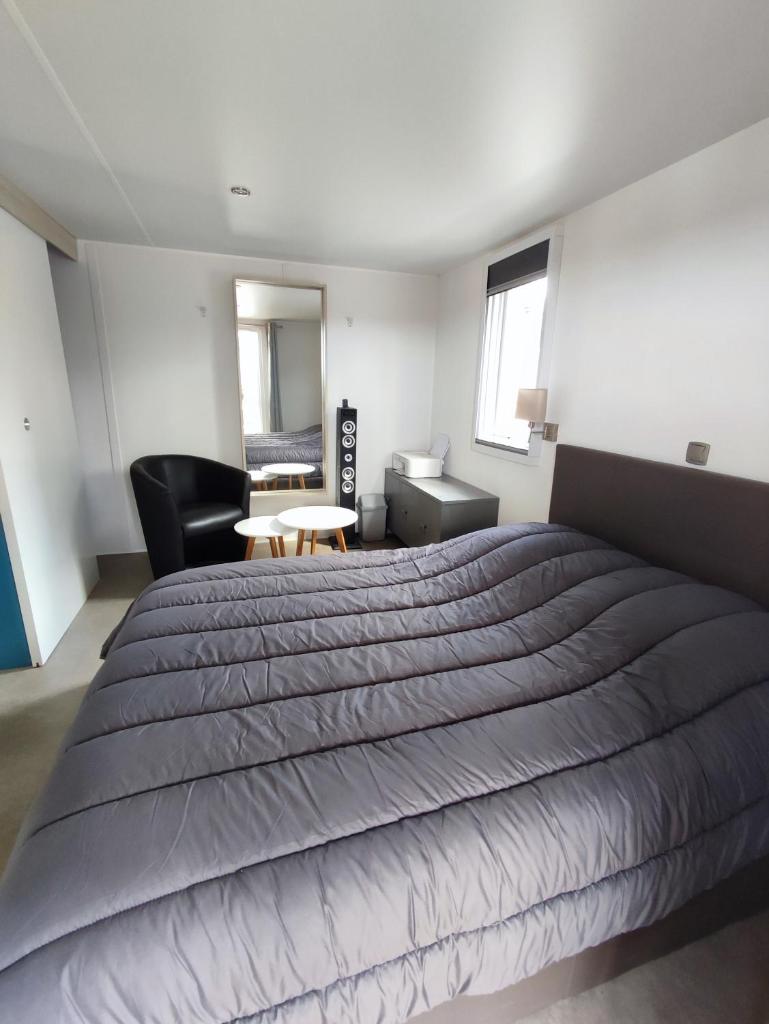 une chambre avec un grand lit et une chaise dans l'établissement LUXUEUX MOBIL-HOME, à Pierrefeu-du-Var
