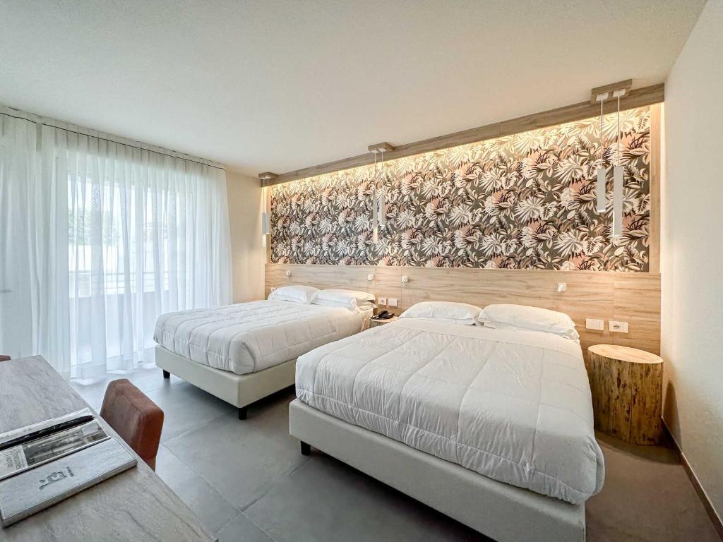 une chambre avec deux lits et un tableau au mur dans l'établissement Bellettini Hotel, à Milano Marittima