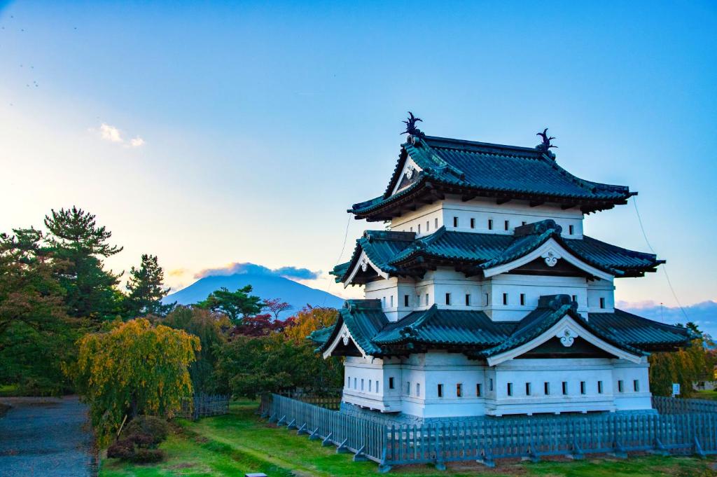 un grand bâtiment blanc avec un toit noir dans l'établissement Kobori Ryokan, à Hirosaki