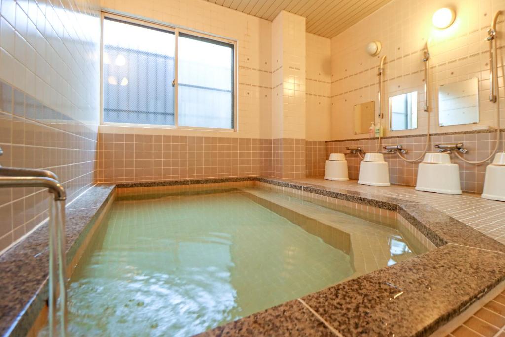 La salle de bains est pourvue d'une grande piscine d'eau. dans l'établissement Kobori Ryokan, à Hirosaki
