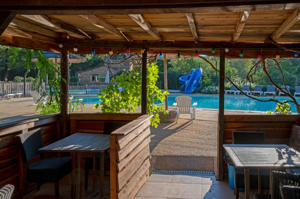 un patio avec une table et des chaises et une piscine dans l'établissement Camping Le Pech Charmant, à Les Eyzies-de-Tayac