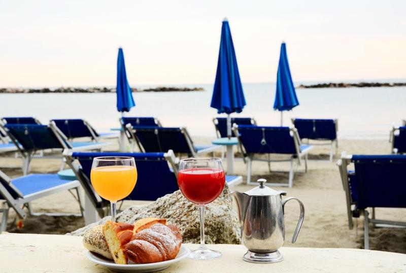 une table avec deux verres de vin et du pain sur la plage dans l'établissement Hotel Crystal - SPIAGGIA INCLUSA con Formula All Inclusive, à Rimini