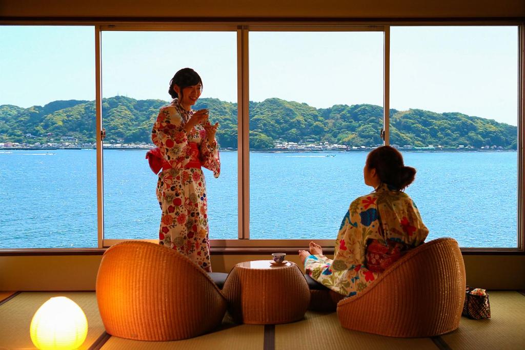 deux femmes en kimono assises sur des chaises regardant l'eau dans l'établissement Ooedo Onsen Monogatari Nanki Kushimoto, à Kushimoto