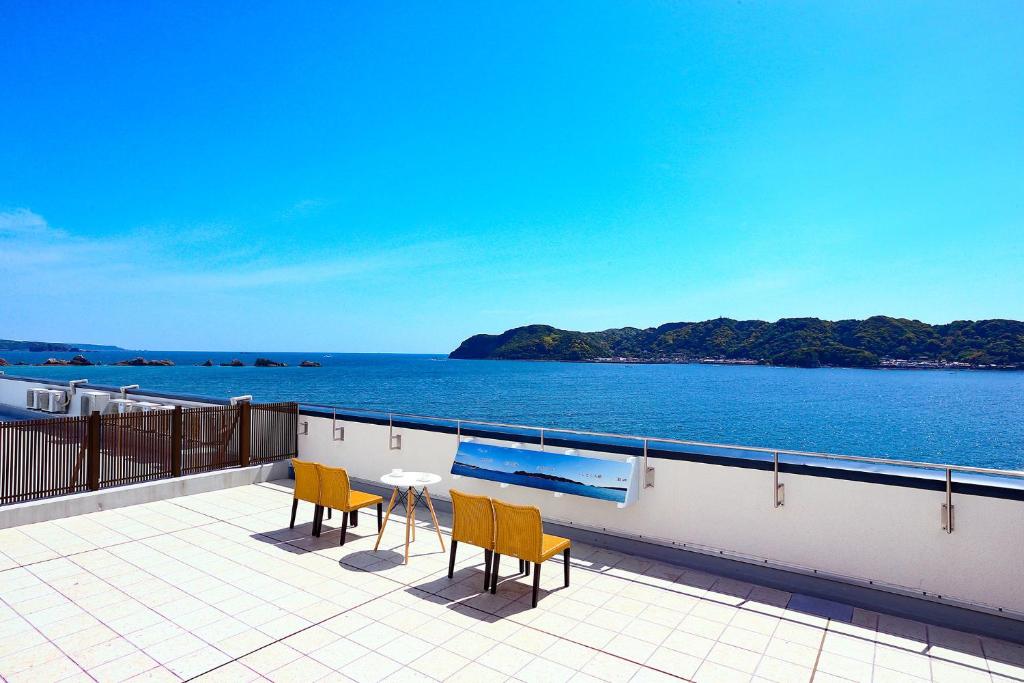 - un balcon avec deux chaises et une table donnant sur l'océan dans l'établissement Ooedo Onsen Monogatari Nanki Kushimoto, à Kushimoto