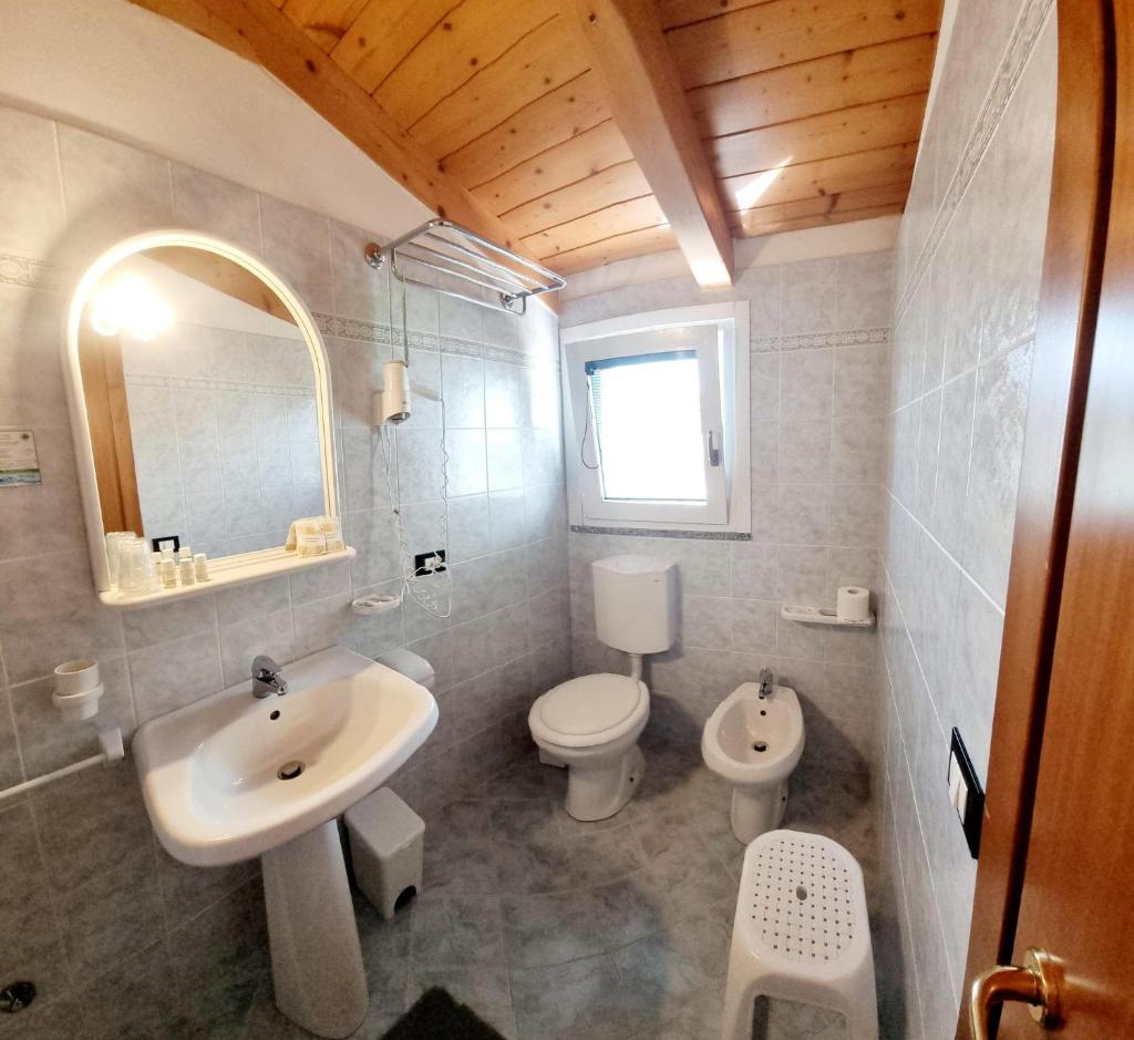 une salle de bain avec un lavabo, des toilettes et un miroir dans l'établissement Hotel Orchidea, à Lignano Sabbiadoro