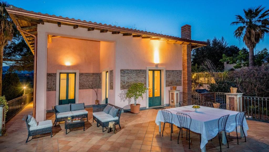 une terrasse avec une table et des chaises ainsi qu'une maison dans l'établissement AGRUME' COUNTRY HOUSE 8, Emma Villas, à Santa Venerina