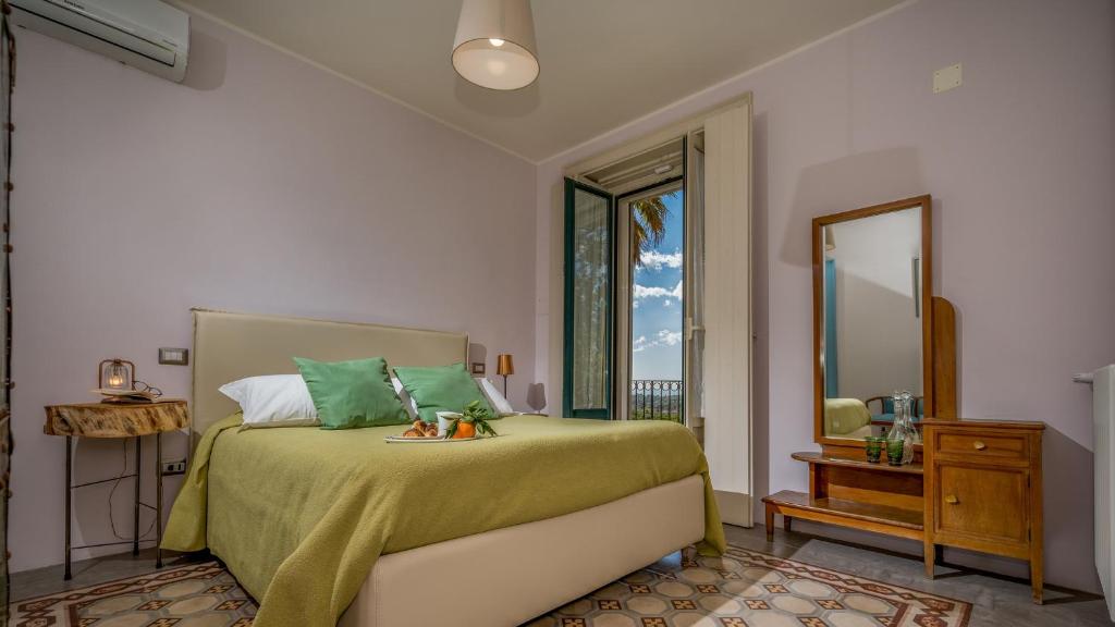 - une chambre avec un lit doté de draps verts et d'un miroir dans l'établissement AGRUME' COUNTRY HOUSE 8, Emma Villas, à Santa Venerina