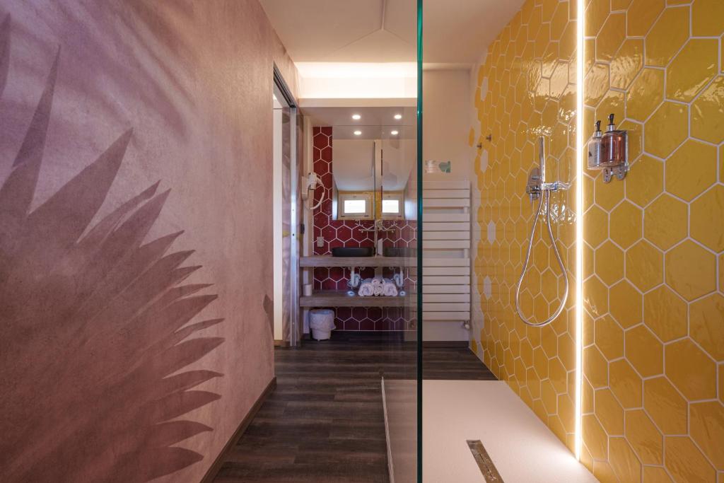 La salle de bains est pourvue d'une douche avec un mur jaune. dans l'établissement Design Hotel Astra B&B, à Misano Adriatico 155 autres photos