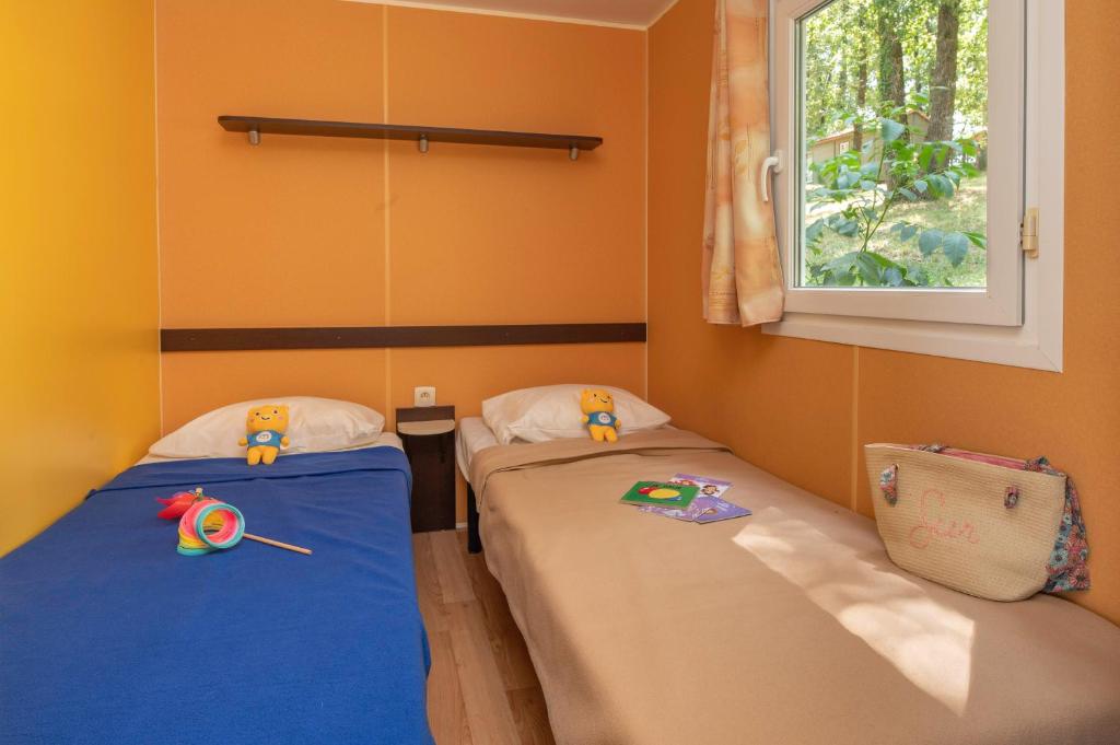 deux lits jumeaux dans une chambre avec fenêtre dans l'établissement Camping maeva Escapades Le Domaine Aramis, à Marsan