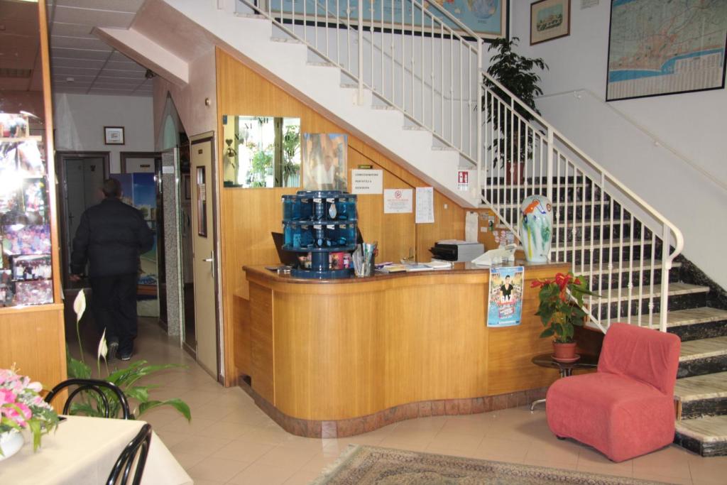 un hall d'entrée d'un magasin avec un comptoir et des escaliers dans l'établissement Hotel Peonia, à Rimini