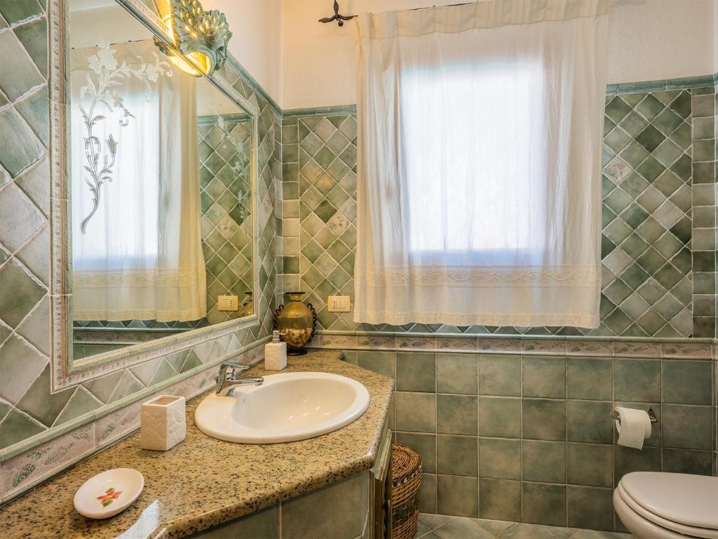 une salle de bain avec un lavabo, des toilettes et un miroir dans l'établissement Sardinia Family Villas - Villa Donatella with private pool, à Arzachena