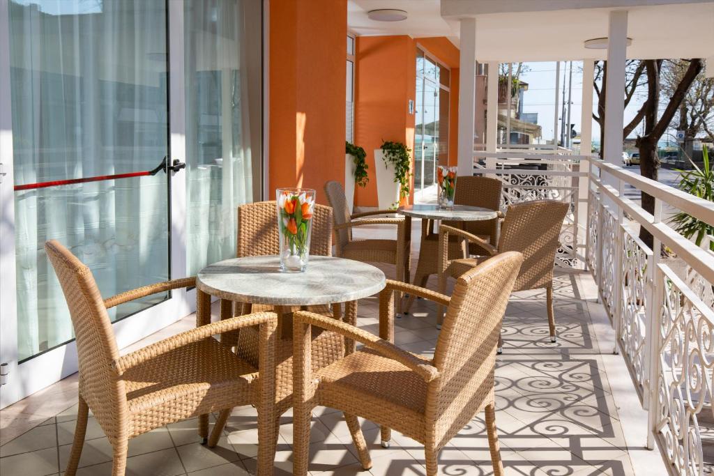 un patio avec tables et chaises sur un balcon dans l'établissement Hotel Ravello Adults Only, à Rimini