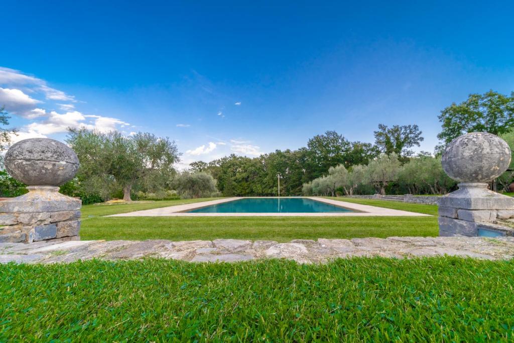 une piscine dans un champ herbeux avec deux statues en pierre dans l'établissement Tenuta le Viste - panoramic Villa, à Scandicci 52 autres photos