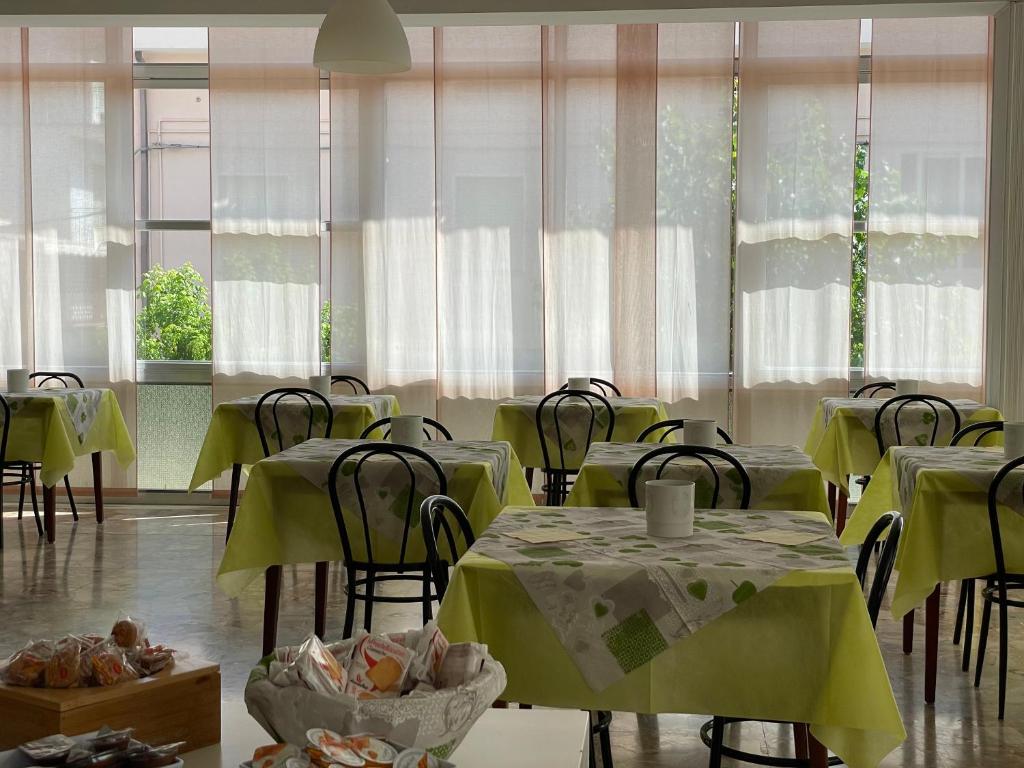 une salle à manger avec tables, chaises et fenêtres dans l'établissement Hotel Apis, à Rimini